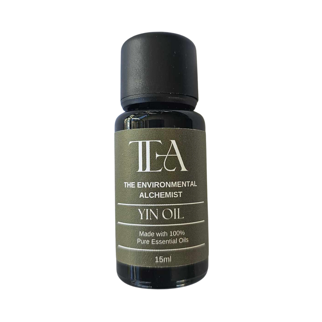 The image shows a bottle labeled "TEA THE ENVIRONMENTAL ALCHEMIST YIN OIL." It states that it is made with 100% pure essential oils and has a volume of 15ml.